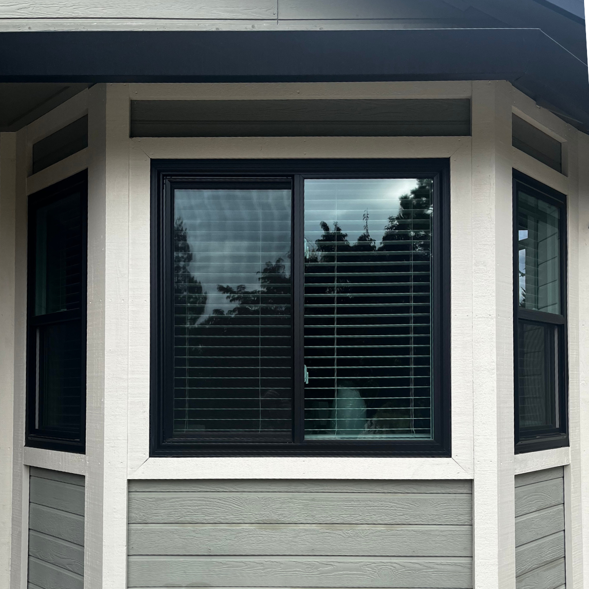 White framed bay window with side panels and black interior frame